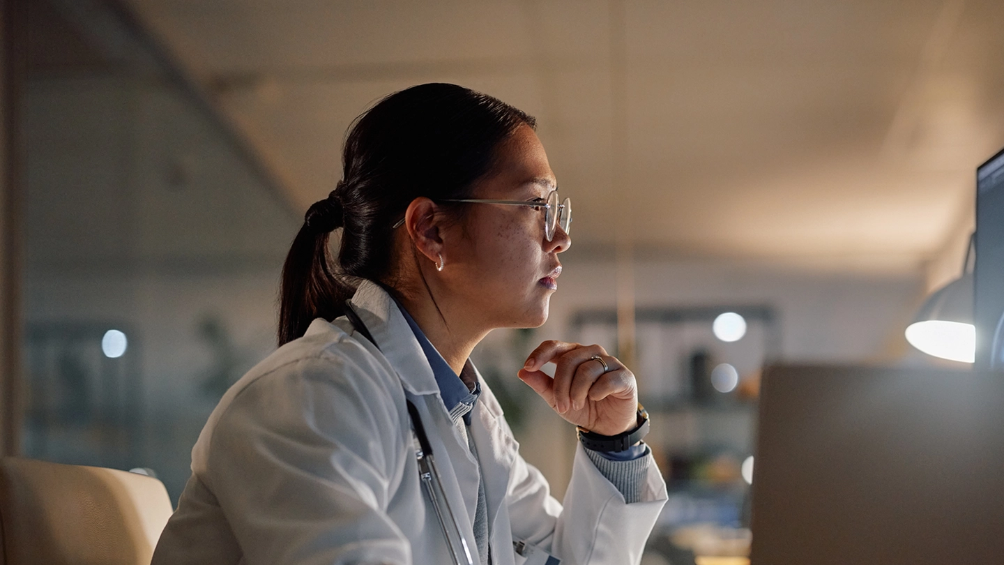Female healthcare professional in white coat and stethoscope at computer during telemedicine consultation